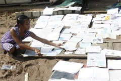 Các em học sinh đang phơi khô sách vở bị ướt do lũ lụt. (Ảnh: Hồ Cầu/TTXVN)