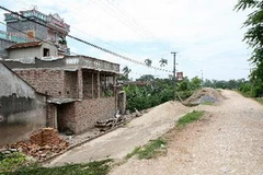 Xây nhà trên đê tả sông Đáy. (Ảnh: Xuân Trường/TTXVN)