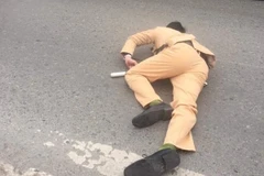 Cú đâm mạnh khiến Trung úy cảnh sát bị thương, nằm bất động trên đường. (Ảnh: PV/Vietnam+)