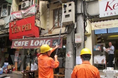 Nhân viên Công ty Điện lực Hoàn Kiếm đang ghi chỉ số công tơ (Ảnh: Đức Duy/Vietnam+)