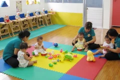 Giáo viên Trường Mầm non Hoa Phương Đỏ, quận Gò Vấp, chăm sóc trẻ từ 6-18 tháng tuổi. (Ảnh: Phương Vy/TTXVN)