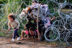 Người di cư vượt qua hàng rào dây thép gai gần Roszke, giáp giới Serbia. (Nguồn: AFP/TTXVN)