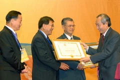 Chủ tịch Ủy ban Trung ương MTTQ Việt Nam Huỳnh Đảm trao Bằng khen của Bộ Ngoại giao cho các kiều bào có công với đất nước. (Ảnh: Nhan Sáng/TTXVN) 