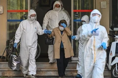 Nhân viên y tế hỗ trợ một bệnh nhân nghi nhiễm COVID-19. (Ảnh minh họa. AFP/TTXVN)