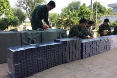 Tổ công tác thuộc Đồn Biên phòng Phước Chỉ kiểm đếm số thuốc lá ngoại thu giữ. (Ảnh: TTXVN phát)