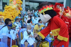 Các em nhỏ giao lưu với đội múa lân. (Ảnh: Văn Dũng/TTXVN)