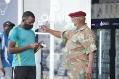 Binh lính Nam Phi tiến hành đo kiểm tra thân nhiệt cho người dân. (Ảnh: TTXVN)