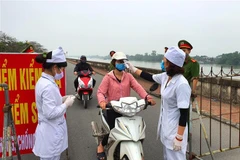 Đo thân nhiệt người qua lại khu đường đê ven sông Đào thành phố Nam Định. (Ảnh: Công Luật/TTXVN)