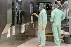 Các kỹ thuật viên giám sát việc sản xuất quy mô lớn và cung ứng vắcxin phòng COVID-19. (Ảnh: AFP/TTXVN)