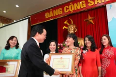 Bộ trưởng Phùng Xuân Nhạ trao bằng khen cho các giáo viên có thành tích xuất sắc trong công tác giáo dục mầm non. (Ảnh: Thanh Tùng/TTXVN)
