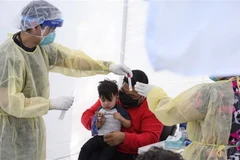 Lấy mẫu dịch xét nghiệm COVID-19 cho trẻ nhỏ. (Ảnh: AFP/TTXVN)