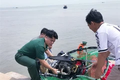 Lực lượng biên phòng trục vớt dù lượn bị rớt trên biển Cần Giờ. (Ảnh: TTXVN phát)