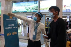 Các nhân viên hướng dẫn hành khách đến khu vực làm thủ tục lên máy bay tại sân bay Tân Sơn Nhất. (Ảnh: Tiến Lực/TTXVN)