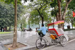 Lao động đạp xích lô ế khách những ngày Hà Nội mưa. (Ảnh: Mai Mai/Vietnam+)
