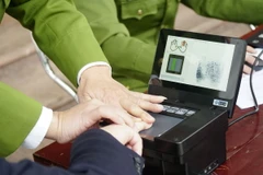 Thủ tục lấy mẫu vân tay. (Ảnh: Xuân Tư/TTXVN)