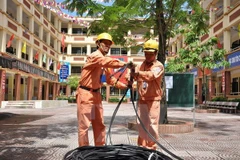 Công nhân điện lực Hà Nội kéo bổ sung nguồn dây cấp điện cho khu dân cư. (Ảnh Mạnh Khánh/TTXVN)