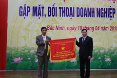 Bí thư Tỉnh ủy Bắc Ninh Nguyễn Nhân Chiến trao cờ thi đua của Chính phủ cho đơn vị có thành tích xuất sắc năm 2017. (Ảnh: Thanh Thương/TTXVN)
