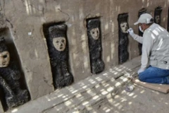 Một nhà khảo cổ làm việc bên những bức tượng gỗ được phát hiện ở Peru. (Nguồn: AFP)