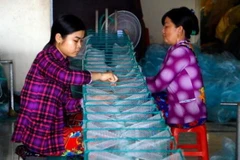 Người dân làng lưới Thơm Rơm tất bật sản xuất hàng phục vụ nhu cầu đánh bắt thủy sản trong mùa lũ. (Ảnh: Thanh Liêm/TTXVN)