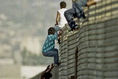 Một nhóm người đang trèo qua hàng rào biên giới để vào Mỹ. Ảnh minh họa. (Nguồn: AP)