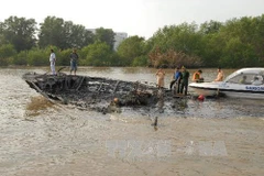 Tàu cánh ngầm Vina Express 01 bị cháy rụi và chìm một phần xuống sông. (Ảnh: Mạnh Linh/TTXVN)