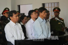 Bị cáo Vũ Việt Hùng (áo xanh bên phải) trước vành móng ngựa. (Ảnh: K' Guih/TTXVN)