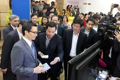 Nhân viên bưu điện trình bày về dịch vụ mới với Phó Thủ tướng Vũ Đức Đam. (Ảnh: T.H/Vietnam+)