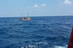 Lai dắt một tàu cá gặp nạn vào bờ. (Ảnh minh họa: Khiếu Tư/TTXVN)