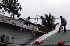 Người dân đặt bao cát đề phòng tốc mái nhà. (Ảnh: Lê Huy Hải/TTXVN)