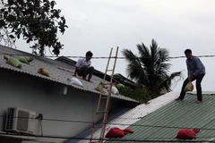 Người dân đặt bao cát đề phòng tốc mái nhà. (Ảnh: Lê Huy Hải/TTXVN)