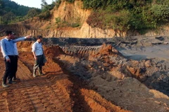 Đoàn công tác kiểm tra hiện trường sự cố vỡ đập bể chứa bùn thải. (Ảnh: Tá Chuyên/TTXVN)