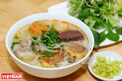 Bún bò Huế ăn cùng với mấy cọng rau húng thơm, chút hoa chuối thái mỏng, mấy múi chanh giấy (chanh cốm) thơm lừng và đặc biệt là ớt xanh của Huế.