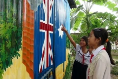 Các em thiếu nhi rất thích thú trước những bức vẽ nhiều màu sắc trên vách nhà. (Ảnh: Chương Đài/TTXVN) 