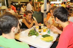 Du khách nước ngoài thưởng thức ẩm thực tại Chợ đêm bến Ninh Kiều. (Ảnh: Thanh Vũ/TTXVN)