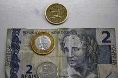 Đồng tiền xu 1 USD của Mỹ (trên) và đồng tiền giấy và tiền xu Real của Brazil. (Nguồn: AFP/TTXVN)