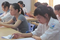 Thí sinh xem lại bảng tuần hoàn hóa học trước giờ thi môn hóa. (Ảnh: Phạm Mai/Vietnam+)