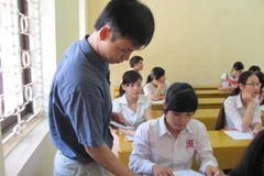 Cán bộ coi thi hướng dẫn thí sinh làm thủ tục tại hội đồng thi Học viện Bưu chính viễn thông. (Ảnh: Phạm Mai/Vietnam+).