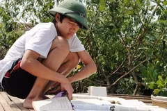 Học sinh rốn lũ miền Trung đang cố "cứu" sách giáo khoa bị ướt. (Ảnh: Mạnh Hùng/Vietnam+).