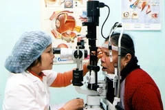 Bác sỹ khám mắt cho người dân. (Nguồn: TTXVN)