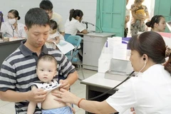 Bác sỹ khám cho bệnh nhân nhi. (Ảnh: Dương Ngọc/TTXVN)