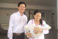 Anh Chiều và chị Thơm phấn khởi đưa cháu bé ra viện. (Ảnh: Vietnam+)