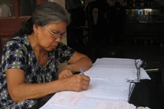 Bà Nguyễn Thị Khoát, một giáo dân đang miệt mài viết những tấm thẻ cử tri. (Ảnh: Thùy Giang/Vietnam+)