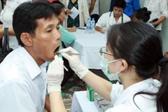 Bác sỹ khám răng cho người dân. (Ảnh: TTXVN)