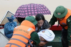 Chiến sỹ biên phòng giúp người dân thoát khỏi vùng lũ. (Ảnh: An Đăng/TTXVN)