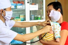 Cán bộ y tế khám dinh dưỡng cho trẻ nhỏ. (Ảnh: TTXVN)