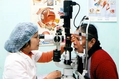 Bác sỹ khám mắt cho người dân. (Ảnh: Hữu Oai/TTXVN)