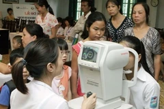 Cán bộ y tế khám mắt cho trẻ em. (Ảnh: Dương Ngọc/TTXVN)