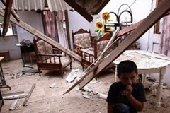 Một cậu bé bên trong ngôi nhà bị hư hại do trận động đất gây ra. (Nguồn: AFP)