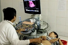 Bác sỹ kiểm tra thai cho thai phụ. (Ảnh: TTXVN)