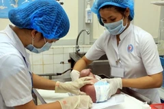 Nhân viên y tế chăm sóc cho trẻ sơ sinh mới trào đời. (Ảnh: Dương Ngọc/TTXVN)
